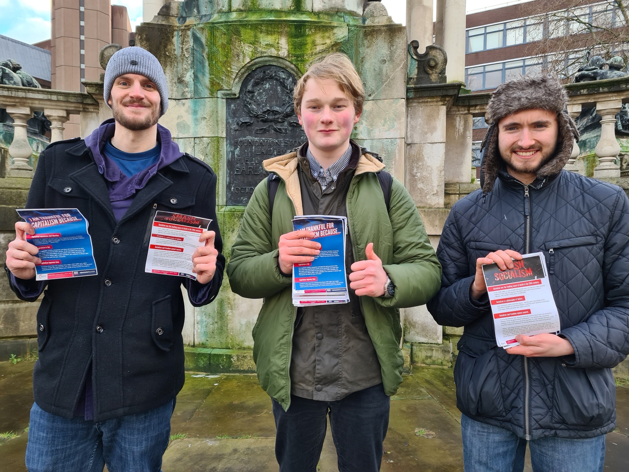 Three activists holding capitalism and socialism leaflets at a Turning Point UK street stall.