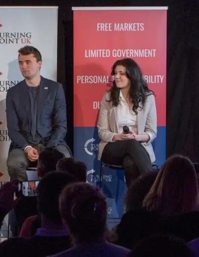 Two speakers on stage with a Turning Point UK banner.