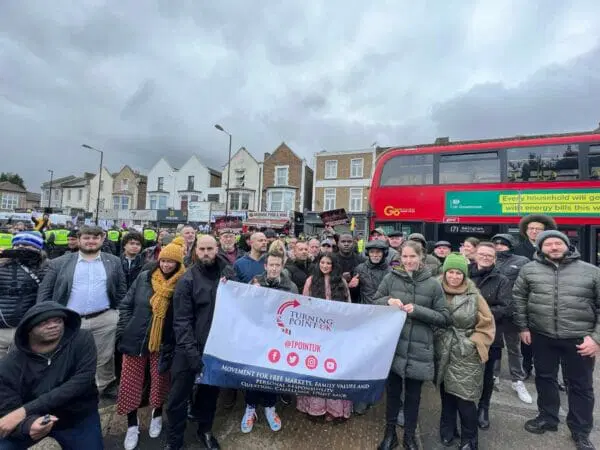Turning Point UK activists holding a banner on a city street.
