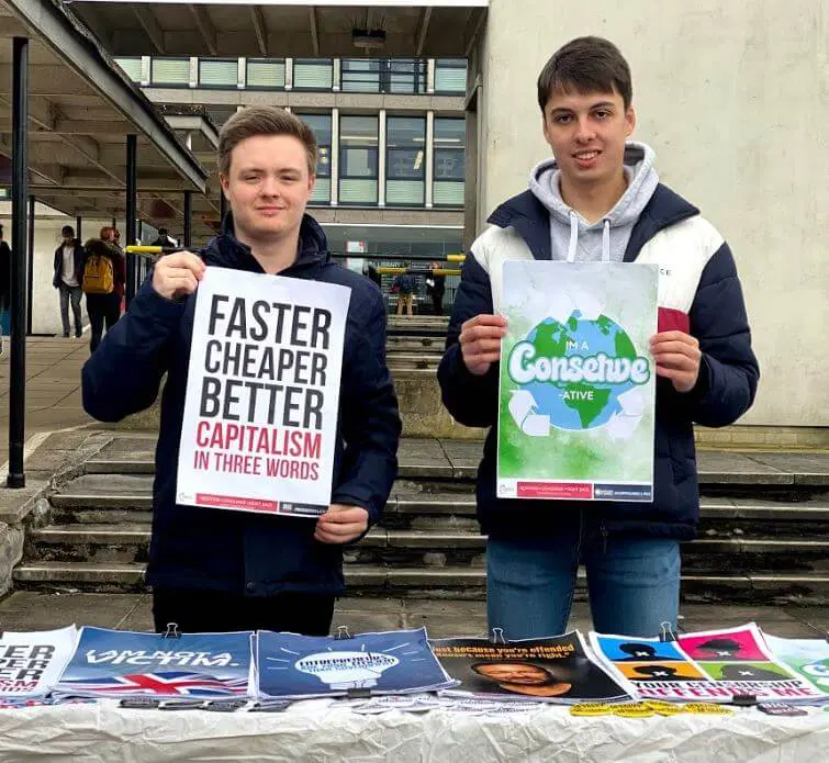 Two TPUK activists holding an I'm a Conservative poster and a capitalism poster on campus.